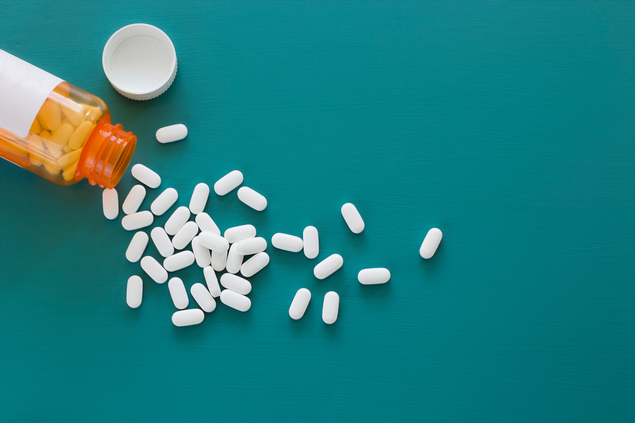 White Pills on a Teal Background